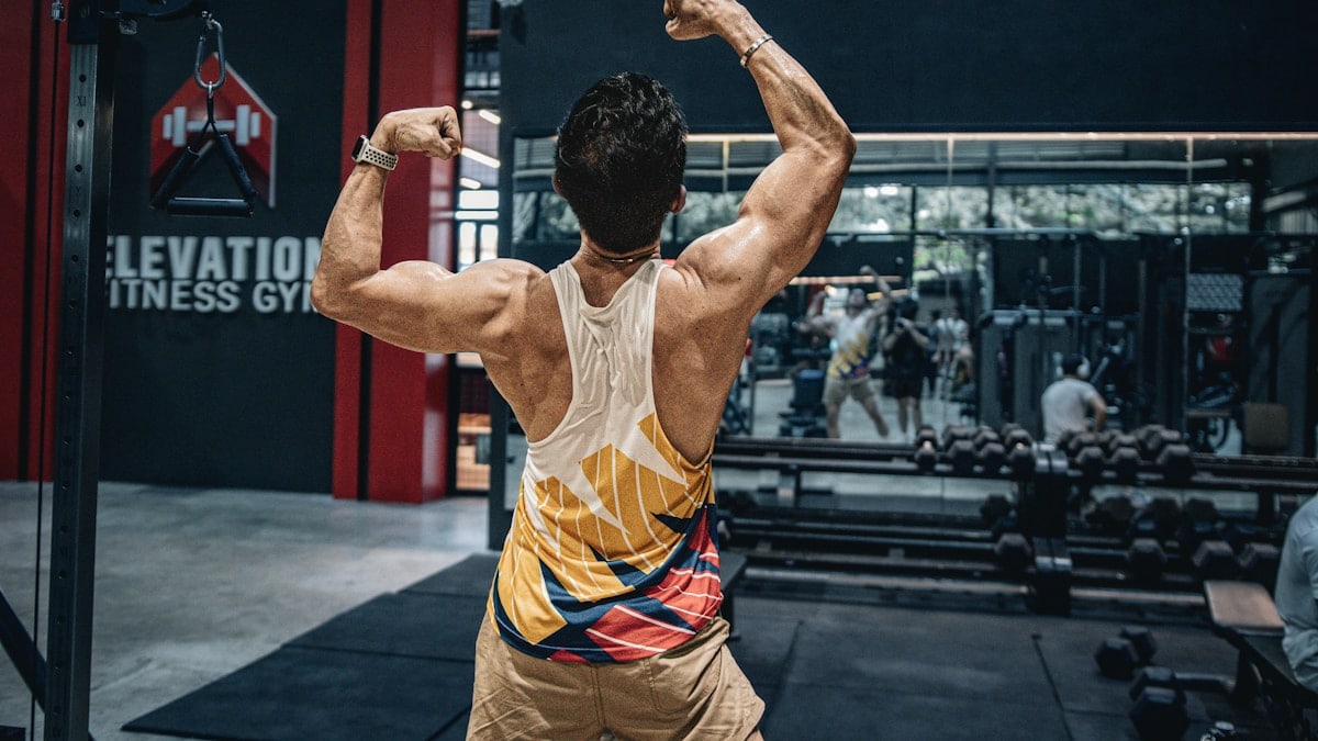 Man flexes muscles in a gym.